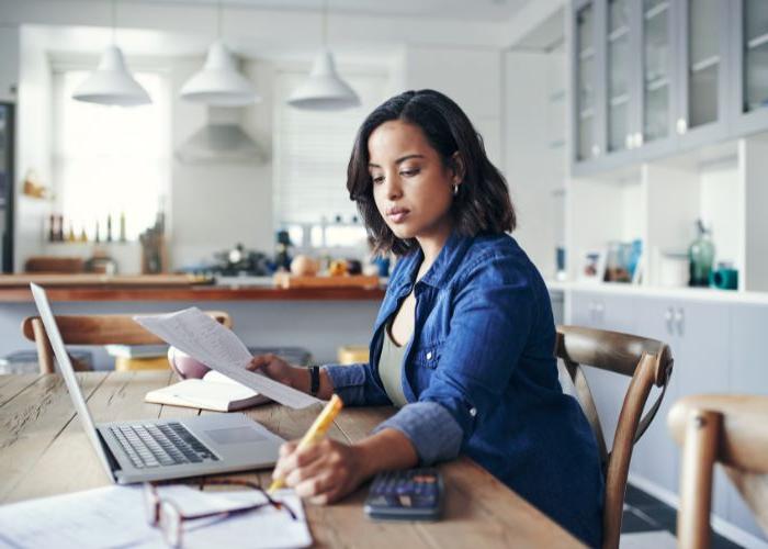 Woman working at a kitchen table on her laptop